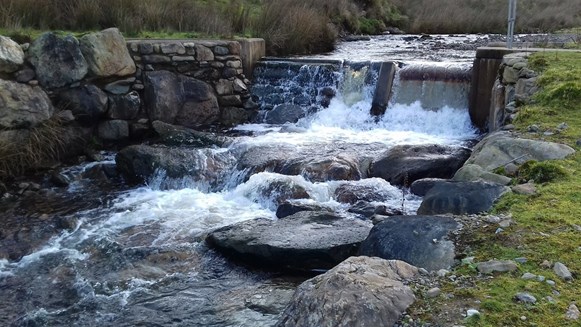 Photograph showing use of large boulders to create pre-barrage plunge pool downstream of a hydropower weir