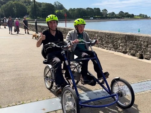 Two people on an adaptive cycle enjoying the Caernarfon section of the Wales Coast Path (Antur Waenfawr)